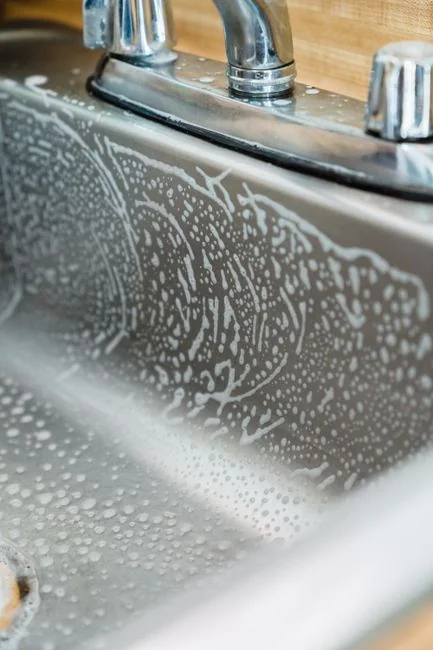 Des laveurs de vitres en hauteur, équipés de protections, nettoient la façade d'un gratte-ciel.